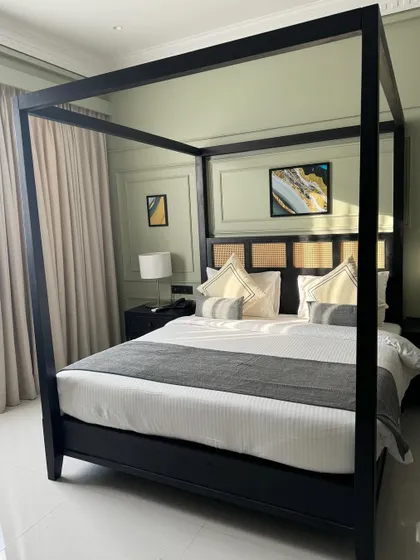 A different view of the modern black canopy bed, highlighting its clean lines and minimalist frame. The matching nightstands and lamps create a symmetrical and balanced look for a sophisticated guest room.