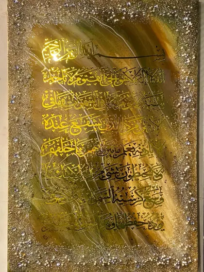 A vertical artwork of Ayat al-Kursi with black calligraphy on a gold background, framed with a glittering border.
