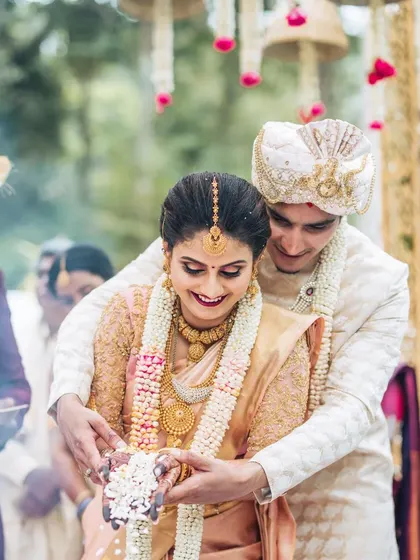 A candid moment of joy during a traditional Hindu ceremony. The couple is surrounded by the warmth of family and the elegance of the custom-designed mandap.