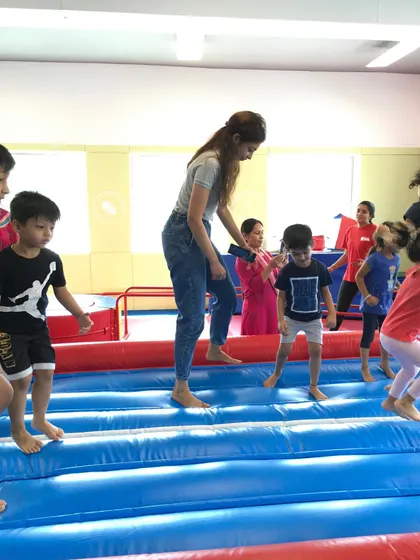 More fun on the tumble track. A parent helps a child jump, highlighting the interactive and family-friendly nature of our special events and camps.