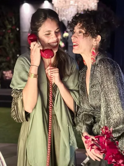 Capturing candid moments of connection and fun. Two guests share a laugh while leaving a joint message, showcasing the interactive and social nature of the audio guestbook experience at an evening sangeet or reception.