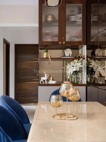 In 'The Adobe' project, the compact dining area was made to feel larger with a mirror wall. The custom Italian marble table is paired with deep blue upholstered chairs for a touch of modern elegance.