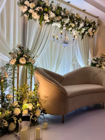 A side angle of the chic engagement stage, highlighting the delicate chandelier and the lush floral arrangements on golden stands.