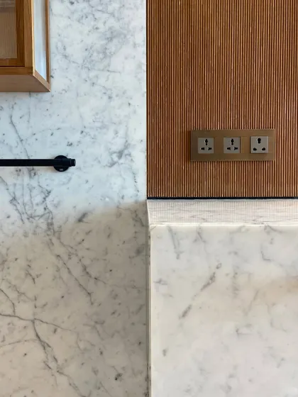 A composition of materials in one of the Worli Duplex bathrooms. Carrara marble, fluted wood, and black metal fixtures come together to create a palette that is both timeless and contemporary.