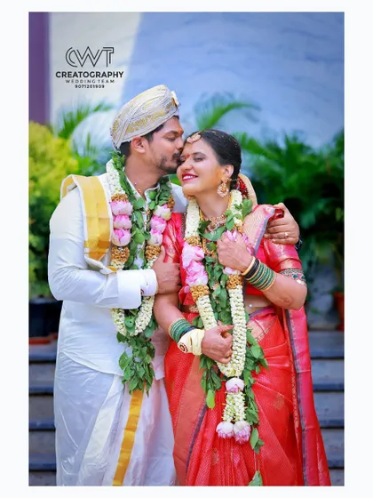 The groom places a gentle kiss on his bride's forehead in this romantic outdoor portrait after their ceremony.