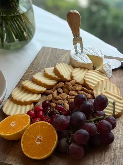 A simple yet elegant cheese board with a wheel of Brie, crackers, almonds, and fresh fruits. The focus is on the quality and classic pairings that never go out of style.