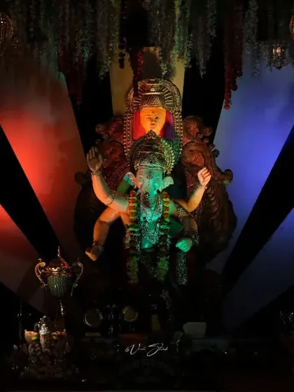 The Palmbeach Cha Vighnaharta idol under dramatic red and blue lighting, showcasing the creative use of light in modern pandals.