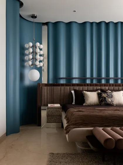 The master bedroom, where the deep blue ripple wall creates a dramatic and luxurious backdrop for the custom bed and statement lighting.