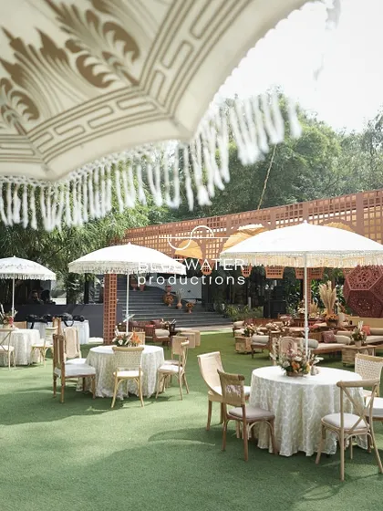Guest seating under large, fringed umbrellas creates a chic and comfortable setting for a sunny afternoon Mehendi.