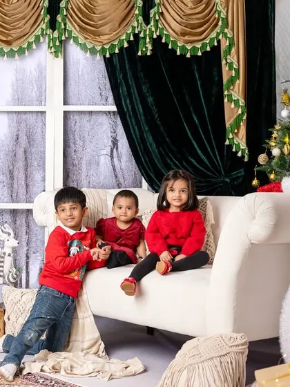 Three siblings enjoying the Christmas setup together, their bright red outfits adding a festive pop of color.