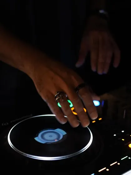 My hands on the mixer in the dark, illuminated by the equipment lights. This captures the mood of a late-night vinyl session, where every adjustment is made by feel.