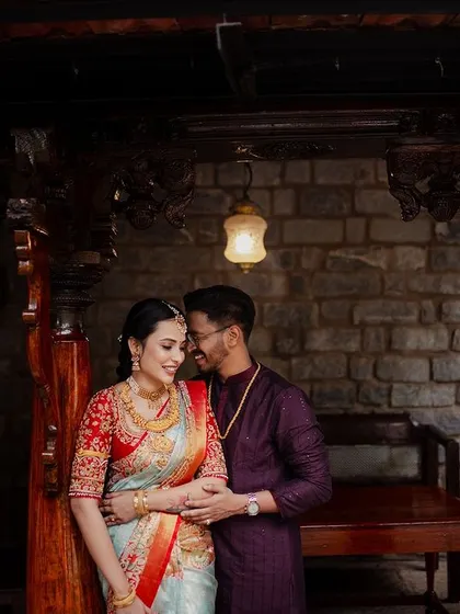 An intimate portrait of a couple, framed by the carved wooden pillars of a traditional seating area.