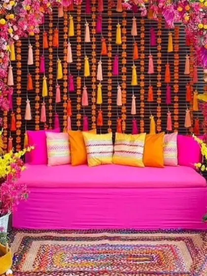 Another view of the vibrant pink Mehandi seating. The combination of the bright pink sofa, colorful cushions, and floral arch creates a perfect photo opportunity.