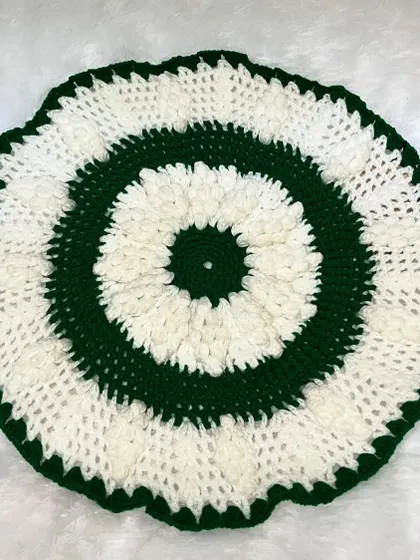 A flat-lay of the green and white table mat, showing the circular pattern and textured stitches.