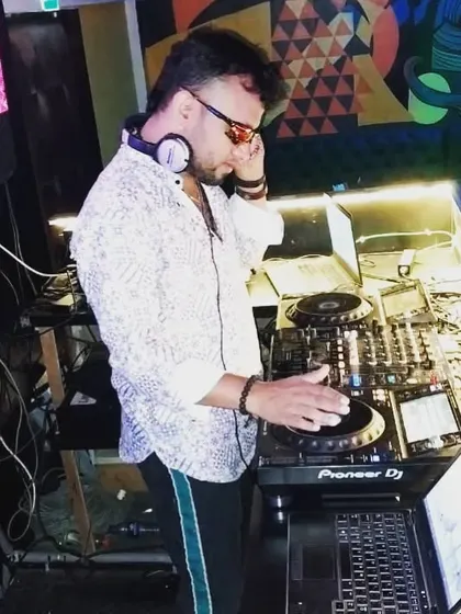A candid shot of me at my workstation, surrounded by multiple laptops and my Pioneer DJ controller, showcasing a complex setup.