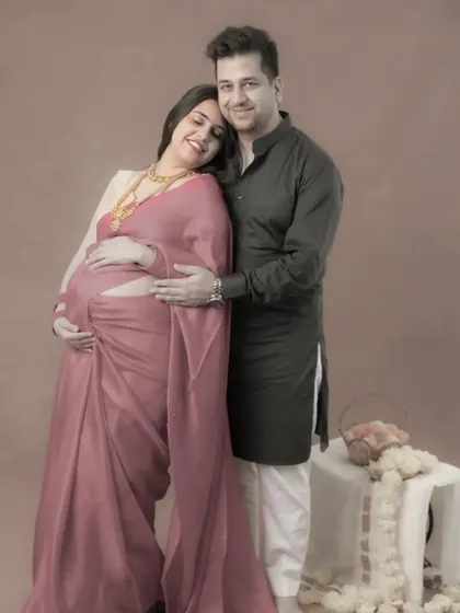 A happy portrait of an expecting couple in traditional Indian wear. Her head resting on his shoulder, this image captures the comfort and joy they find in each other.