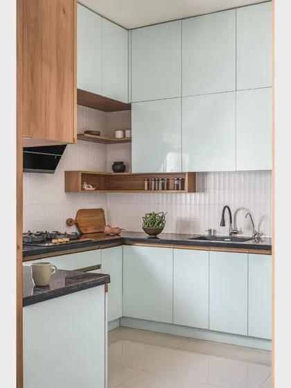 Another view of 'The Boho Escape' kitchen, showing the combination of pastel blue and oak wood laminate. The reflective surfaces and light colors make the space feel bright and open.