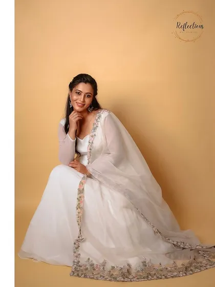 A smiling portrait of the model in the white Anarkali.