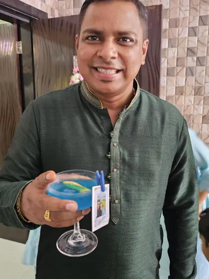 A guest enjoying a vibrant blue cocktail, complete with a personalized photo tag of the couple. These small details make a big impression.