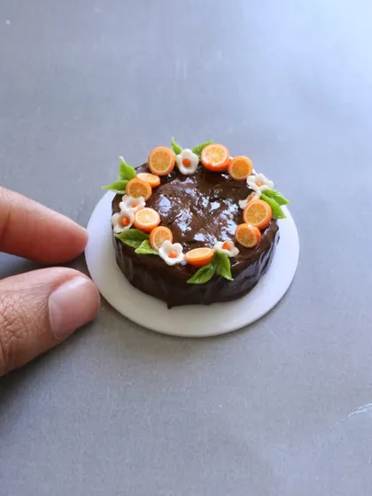 A close-up of the chocolate fruit cake, showing the tiny, detailed orange slices and flowers.
