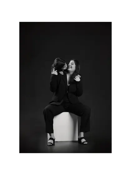 A playful, candid moment between mother and daughter becomes a piece of art in black and white. The focus is entirely on their interaction and the joy in their expressions.