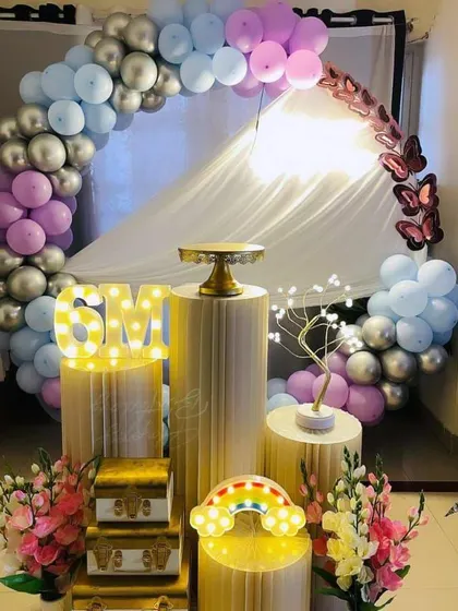 A half-birthday (6 months) celebration with a pastel balloon arch, light-up '6M', and decorative props.
