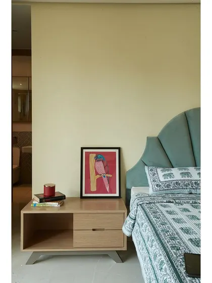 A detail shot of a bedside table, showing how simple furniture and personal art can create a charming vignette.