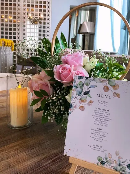 A beautiful and elegant centerpiece with pink roses in a golden hoop, a menu card, and a flameless candle for a soft glow.