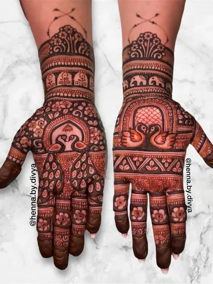 A beautiful symmetrical design featuring peacocks and swans under ornate arches. The wrists are adorned with a band of elephants, adding to the traditional charm.