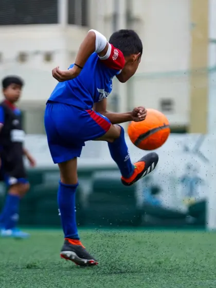 A player perfects his first touch, controlling an orange ball with precision. Mastering the fundamentals is key to our training philosophy.