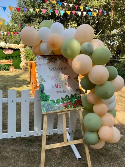 A jungle-themed welcome sign on an easel, adorned with green and peach balloons, ready to greet the birthday guests.