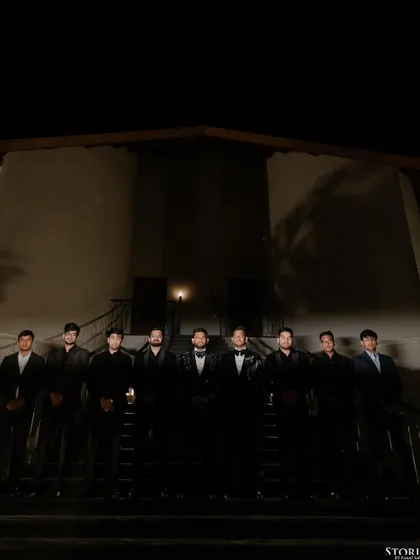 A moody, dramatic group portrait of the groom and his groomsmen, lined up on a staircase at night.