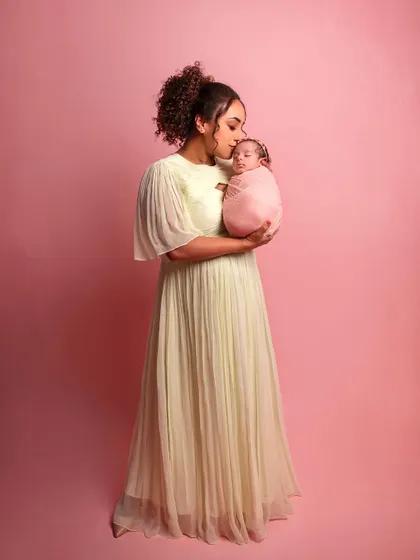 A full-length portrait of Pearle holding her baby, a gentle kiss on the forehead. A beautiful image of motherly love.