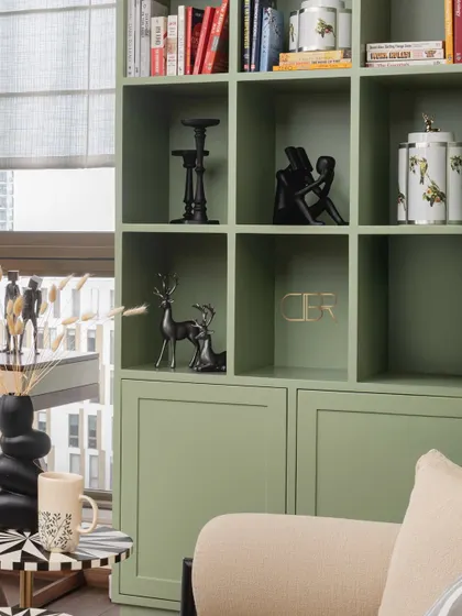 A close-up of the custom sage green bookshelf in the master bedroom. The arched niches and curated decor objects reflect my belief in creating storage solutions that are both beautiful and personal, turning everyday items into a design feature.
