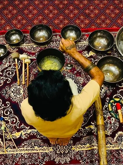 An overhead view of my sound healing setup for a corporate session at The Oberoi. You can see the arrangement of singing bowls, a handpan, chimes, and other instruments on a traditional carpet.