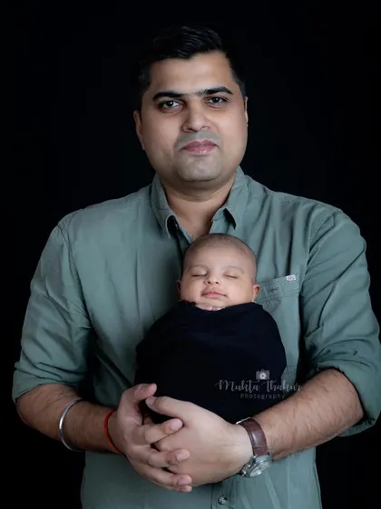 A proud father holding his precious newborn. The simple black background makes this tender moment stand out.