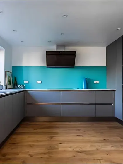 This minimalist kitchen uses handle-less grey cabinets and a bright teal backsplash for a pop of color.