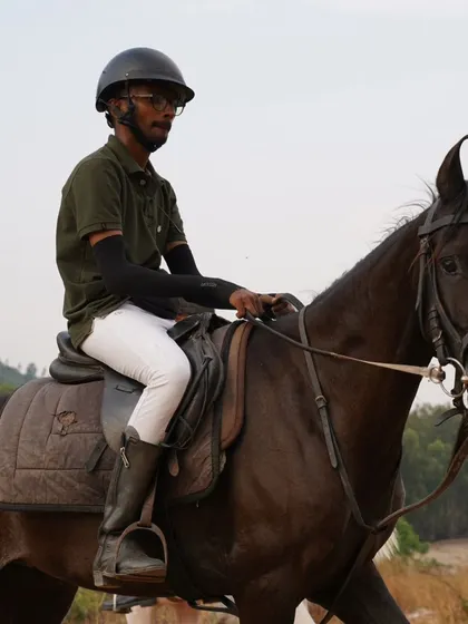 A rider on a dark horse during a trail ride, demonstrating the calm and steady nature of our horses in an outdoor environment.