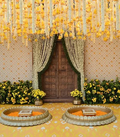The Haldi ceremony seating, with large brass urlis ready for the turmeric paste, set against a backdrop of hanging floral strings.