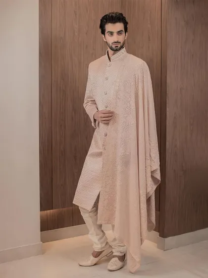 The epitome of modern royalty. This rose gold sherwani, paired with a fully embroidered stole, offers a contemporary yet timeless option for the modern groom, perfect for a grand wedding ceremony or reception.