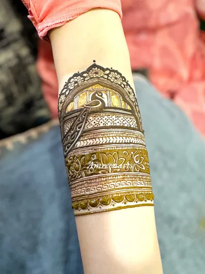 A close-up of an arm band featuring a peacock in a jharokha (window), a classic royal motif.