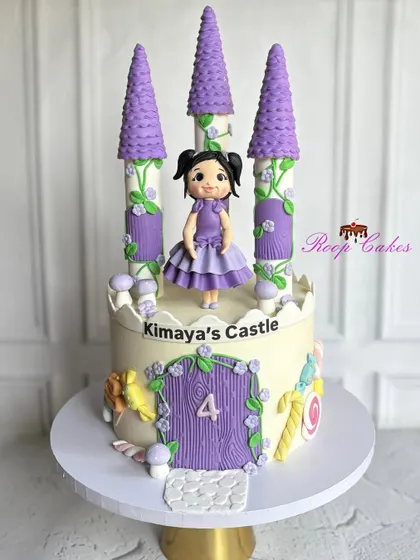 Welcome to Kimaya's Castle, where fairytales come true. This whimsical cake features lavender towers, a princess figurine, and sweet candy details for a magical 4th birthday.
