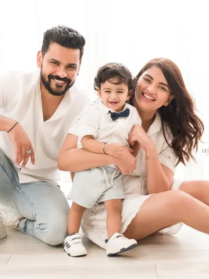 A picture-perfect family of three. Their coordinated white outfits and bright smiles make for a classic and joyful family portrait.
