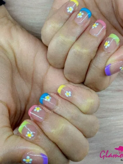 A fresh and fun take on the French manicure, this design features multi-colored pastel tips and is adorned with small, hand-painted white daisies.