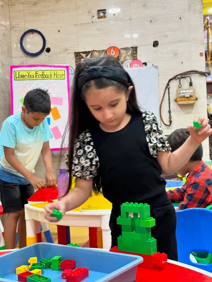 A young girl selects pieces from a bin, fully immersed in the creative process of building.