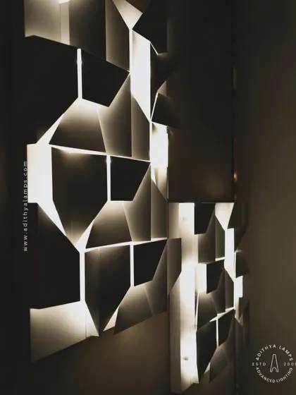 This 3D geometric wall light plays with light and shadow. The puzzle-like arrangement of white panels creates pockets of light, turning a simple wall into a dynamic feature. It is a perfect piece of illuminated wall art.
