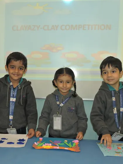 Three students proudly present their finished clay art, each showcasing a unique interpretation of the aquatic theme.