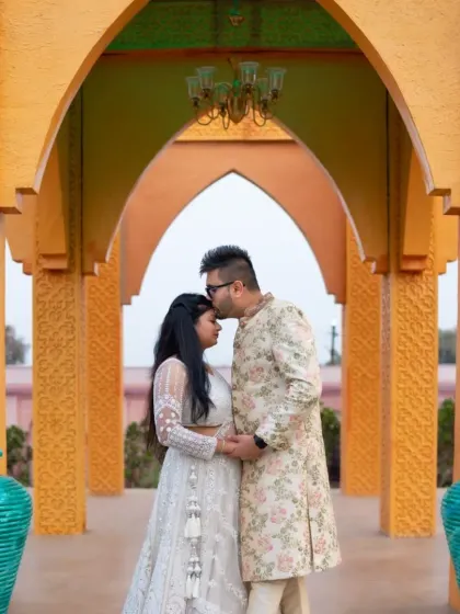 A royal and elegant pre-wedding portrait. The groom's floral sherwani and the bride's white lehenga create a perfectly coordinated and majestic look.