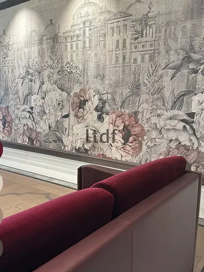 We believe in the power of color psychology. Here, a deep red sofa makes a bold statement against a delicate, large-scale floral and architectural mural. The color choice adds energy and passion to a space grounded in classic elegance.