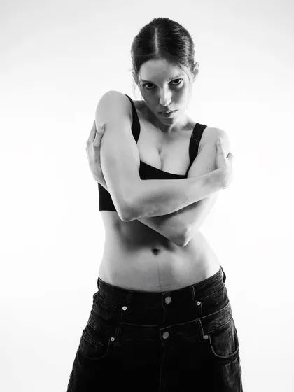 A self-embracing pose that feels both vulnerable and strong, enhanced by the high-contrast black and white.